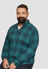 Türkises, kariertes Hemd mit ausgebreitetem Kragen und langen Ärmeln, das ein dunkles Gittermuster und eine textile Struktur aufweist.