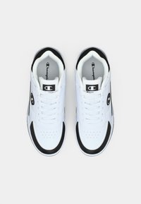 Άσπρα αθλητικά παπούτσια με μαύρες λεπτομέρειες, που διαθέτουν λεία υφή δέρματος, διάτρητο μπροστινό μέρος και μαύρο λογότυπο στο πλάι και στη γλώσσα.