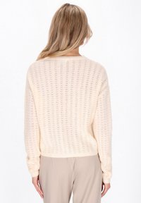 Licht crèmekleurige, gebreide trui met een losse pasvorm, voorzien van een kantachtig patroon, geribbelde manchetten en een ronde halslijn. Geschikt voor diverse outfits.