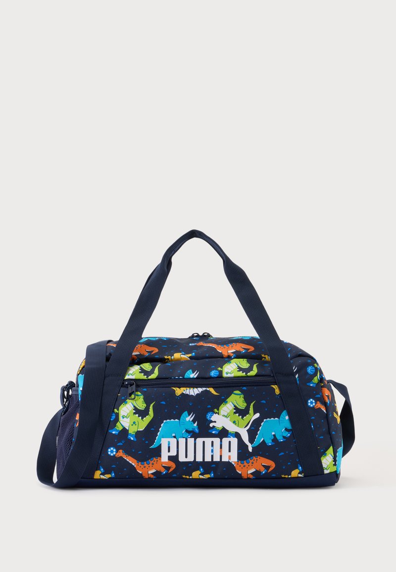 Μικρή σκούρα μπλε τσάντα Puma με πολύχρωμο σχέδιο δεινοσαύρων και σκούρες μπλε λαβές και ιμάντα ώμου.