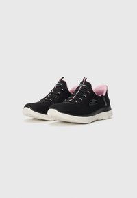 Juodos ir rožinės žemo kirpimo Skechers sportbačiai su elastingomis raištelėmis ir baltais guminiais padais, šiek tiek pasukti į dešinę ant baltos fono.