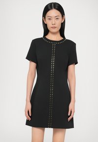 Černé krátké šaty s krátkými rukávy vyrobené z hladké látky, dekorované středovým páskem zlatých cvočků na přední straně a s kulatým výstřihem.