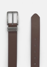 Brown leather belt with a silver metal buckle. Features engraved branding and multiple adjustment holes along the strap.