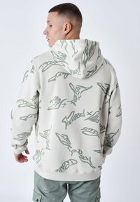 Hætte sweatshirt i lys beige med grønne abstrakte mønstre. Har en afslappet pasform, rib-strikkede ærmer og talje, lavet af blødt stof.