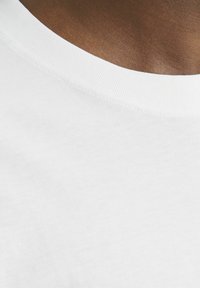 Weißes Baumwoll-T-Shirt mit rundem Halsausschnitt und geripptem Besatz, das eine glatte Textur und subtile Nähdetails zeigt.