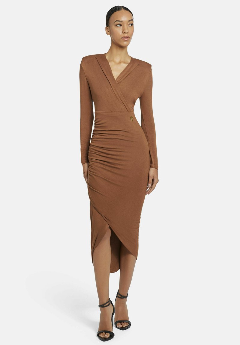 Braunes Wickelkleid mit langen Ärmeln und gerafftem Rock, ausgestattet mit einem Seitenschlitz und einem goldenen Akzentdetail in der Taille. Weicher, strukturierter Stoff.