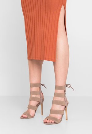 Sandales à talons hauts beiges avec plusieurs sangles en tissu et une semelle lisse, dotées d'un talon aigu slim et de liens à la cheville.