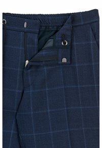 Námořnické modré kostkované kalhoty s texturovaným povrchem, se snadno přizpůsobivým elastickým pasem, šňůrkou a kapsami na zip. Výrazný kostkovaný vzor jako akcent.