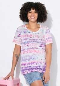 Kortærmet, løstsiddende t-shirt i hvid med pink, lilla og blå abstrakte mønstre; har rund hals og blød tekstur.