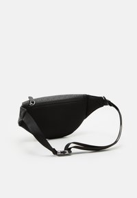 Marsupio nero con fronte testurizzata, tessuto mesh, dettagli in pelle liscia e un compartimento con zip accompagnato da una tracolla regolabile.