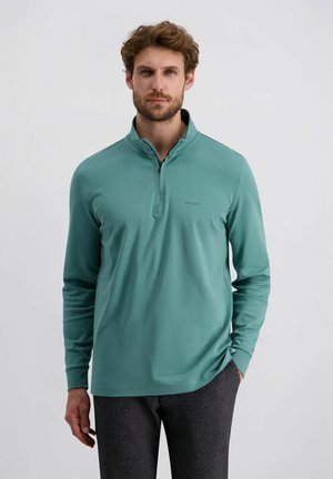 Hellblauer Langarmpullover mit einem halben Reißverschluss am Kragen. Glatte Textur und figurbetonter Schnitt, mit einem dezenten Logo auf der Brust.