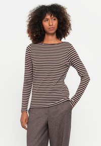 Braun-weiß gestreiftes Langarmshirt mit U-Boot-Ausschnitt, aus weichem Material, kombiniert mit grauen strukturierten Hosen.