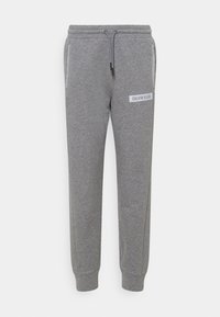 Grijze sweatpants met een elastische tailleband, trekkoord en zijzakken. Bevat een wit label met "CALVIN KLEIN" op de voorkant.