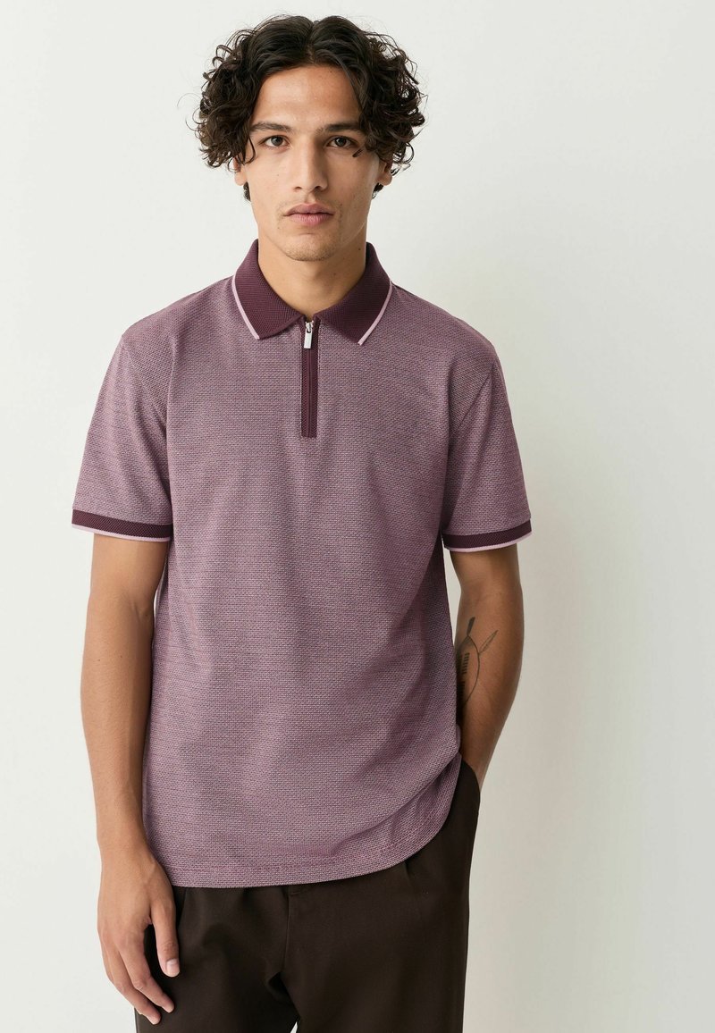 Tricou polo scurt cu mânecă, de culoare vișinie, cu guler cu fermoar, dintr-un material texturat, cu detalii de margine contrastante închis la culoare la guler și la mâneci.