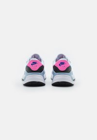 Le sneakers Nike Air presentano una tomaia in rete bianca e grigia chiara, dettagli neri e una linguetta posteriore audace in rosa e blu con il logo "Nike Air".