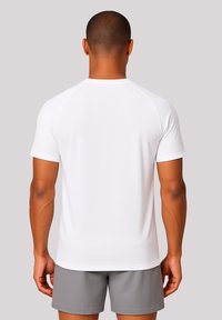 White short-sleeve athletic shirt with a smooth texture and raglan sleeves, paired with grey shorts, viewed from the back.