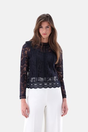 Navy lace top with long sleeves, featuring floral patterns and scalloped hem. Paired with white wide-leg pants.