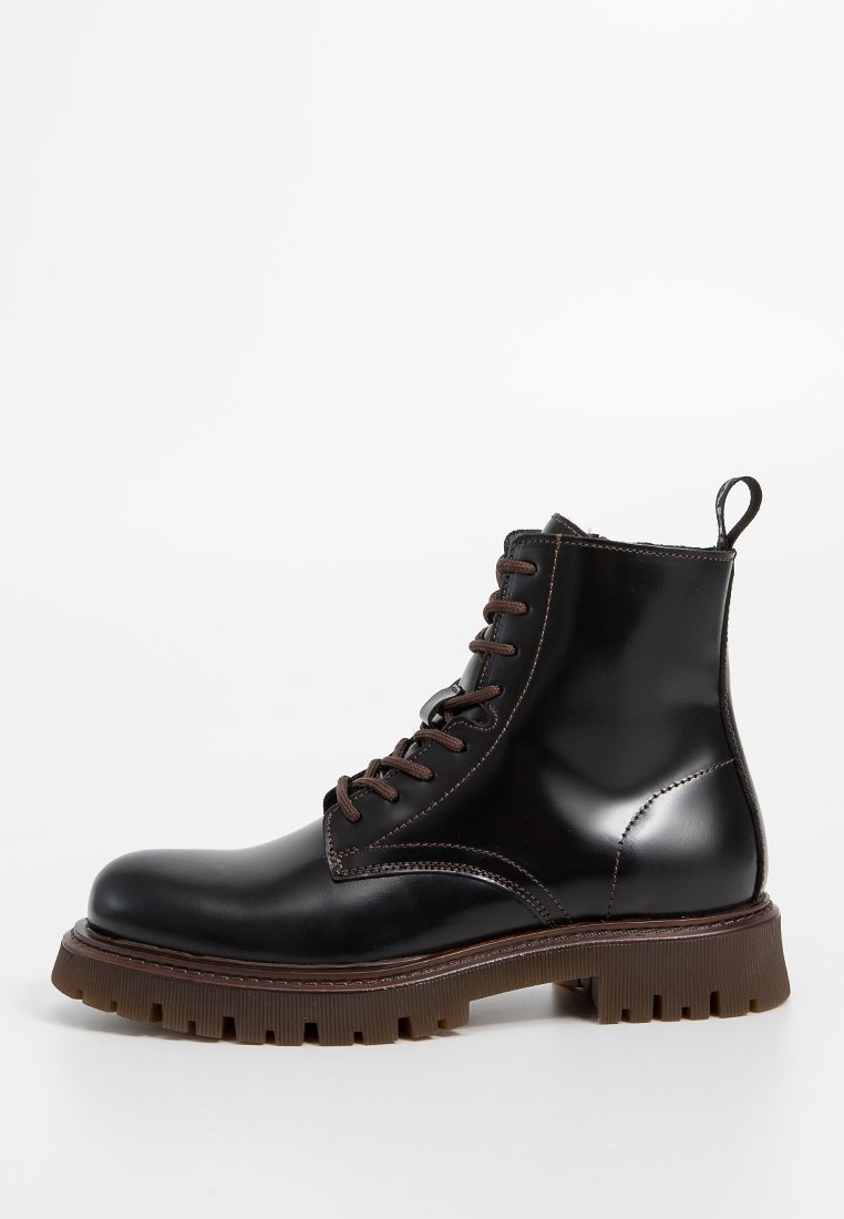 Schwarze Leder-Ankle-Boots mit brauner Naht, Schnürdesign, runder Zehenform und klobiger brauner Gummisohle mit tiefen Grip-Mustern.