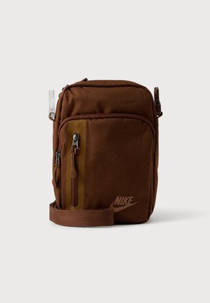 Sac bandoulière Nike marron avec une poche avant zippée, une bandoulière réglable et des compartiments latéraux, présenté sur un fond uni.