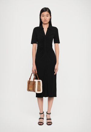 Black, short-sleeve dress with front buttons and ruched detailing. Model holds a brown and cream handbag labeled "Love Moschino" and wears black heels.