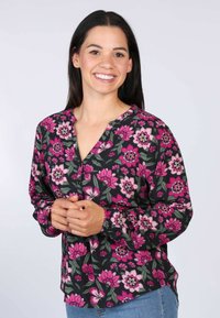Blumenbluse mit schwarzem Hintergrund, die mit rosa und grünen Blumenmustern versehen ist. Sie hat eine Knopfleiste, lange Ärmel und eine lockere Passform.