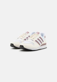 White and light grey sneakers with brown stripes, mesh and suede materials, round toe, flat rubber sole, and lace-up closure.