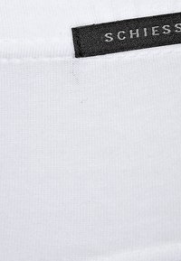 Tessuto di cotone bianco con una trama a coste, caratterizzato da un'etichetta in tessuto nero impresso con il nome del marchio "SCHIESSER."