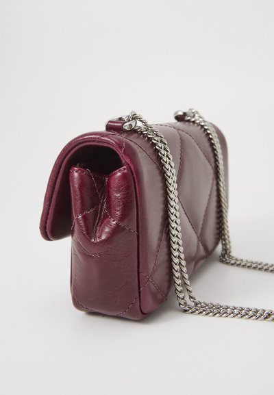 Geantă din piele quilted de culoare burgundă, cu un vârf rotunjit, curea din lanț argintie și un design mic și îngust. Detalii vizibile ale texturii și cusăturii.