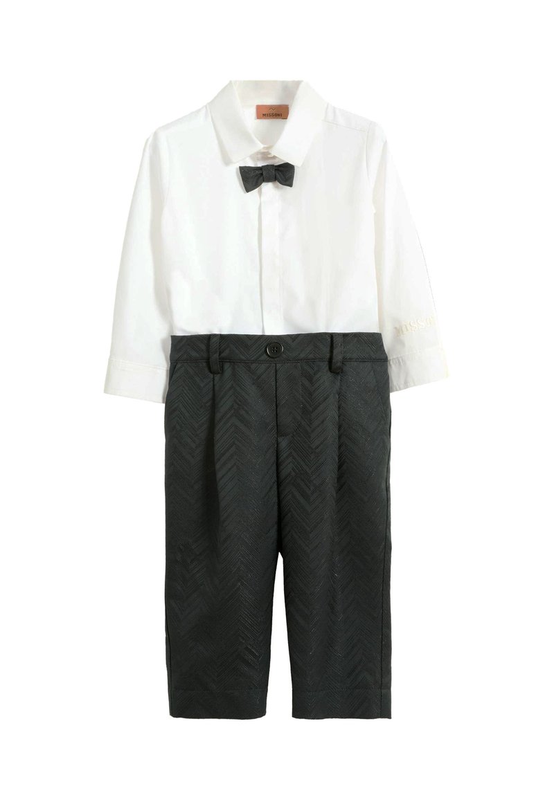 Biała koszula z kołnierzykiem i muszką, połączona z ciemnoszarymi szortami w wzór jodełki, z szlufkami na pasek. Bluzka ma długie rękawy.