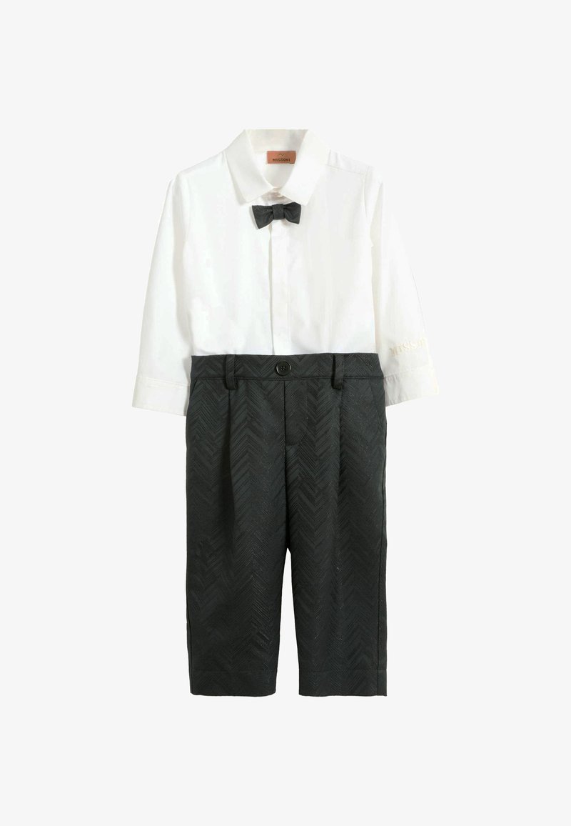Biała koszula z kołnierzykiem i muszką, połączona z ciemnoszarymi szortami w wzór jodełki, z szlufkami na pasek. Bluzka ma długie rękawy.