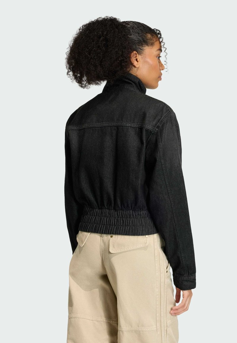 Veste en denim noir avec un col montant, une taille élastiquée et des manches longues. Le dos présente une finition lisse et propre sans embellissements.