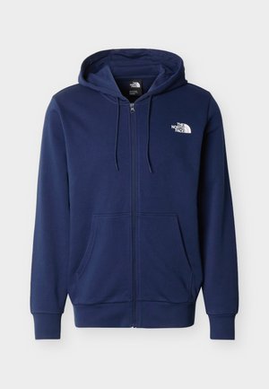 Sweat à capuche zippé bleu marine avec poches avant et logo blanc "The North Face" sur le côté gauche de la poitrine.