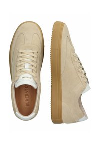 Beige nubuk sneakers dengan aksen putih, desain tali, sol karet gum, dan detail tekstur pada bagian atas untuk cengkeraman dan gaya.