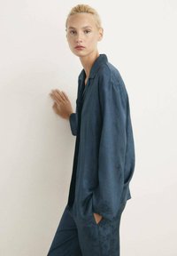 Mörkblå satin loungemössa med en skjorta med krage i avslappnad passform och blommönster, tillsammans med matchande byxor.