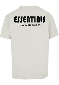 Camiseta de algodón gris claro con mangas cortas que presenta texto negro en la parte trasera: "ESSENTIALS" en la parte superior y "NEW GENERATION" debajo.
