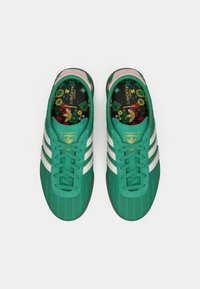 Πράσινα αθλητικά παπούτσια με τρεις λευκές ρίγες. Υφασμάτινο επάνω μέρος με υφή, επενδυμένο κολάρο και εσωτερικό πέλμα με λουλουδένιο σχέδιο. Λαστιχένια σόλα για πρόσφυση.
