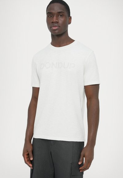 T-shirt blanc à manches courtes en tissu légèrement texturé, avec un logo gris subtil imprimé sur le devant et un col rond.