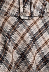 Karo-Stoff in Beige, Grau, Schwarz und Orange. Verfügt über eine glatte Textur mit einer Falte und Gürtelschlaufen oben und zeigt ein gewebtes Muster.