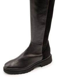 Knielanger schwarzer Lederstiefel mit glatter Textur, kontrastierendem Wildledereinsatz, rundem Zeh und Gummisohle mit dezentem Profil.