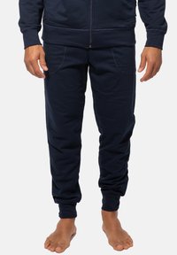 Navyblaue Baumwoll-Jogginghose mit entspannter Passform, ausgestattet mit zwei Seitentaschen und elastischen Bündchen an den Knöcheln. Weicher Stoff und schlichtes Design.