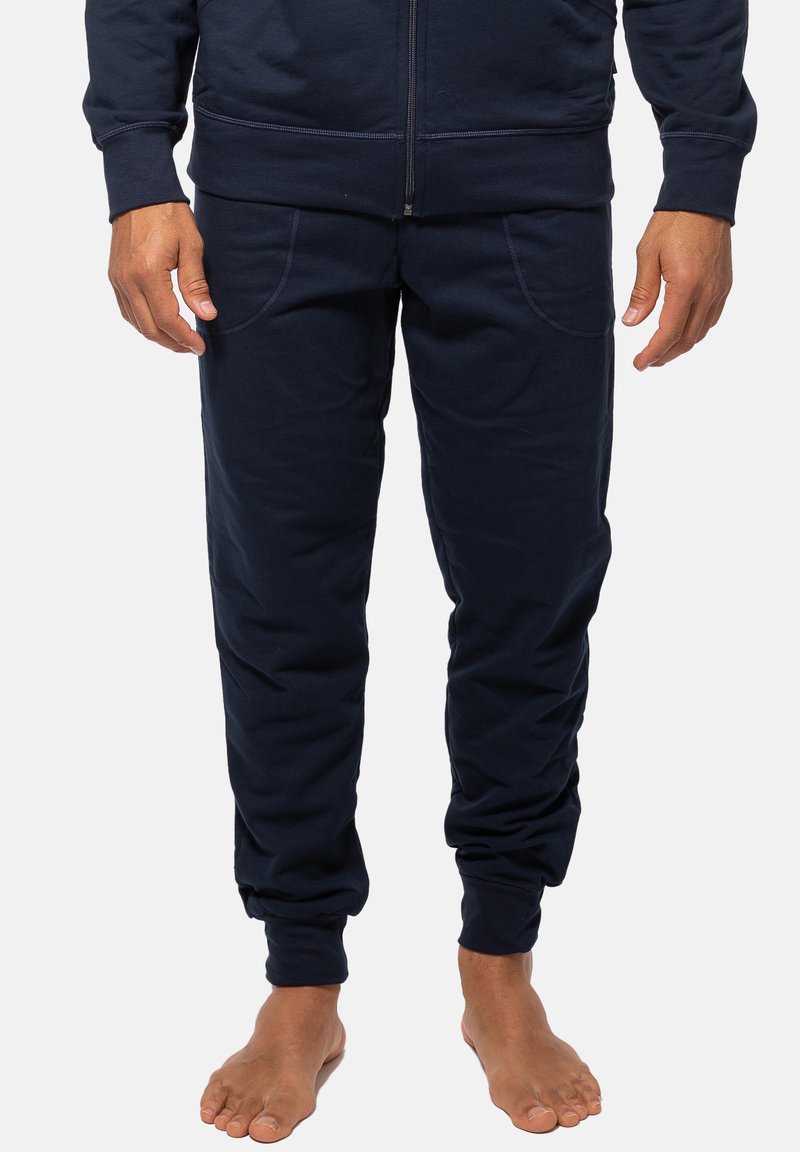 Navyblaue Baumwoll-Jogginghose mit entspannter Passform, ausgestattet mit zwei Seitentaschen und elastischen Bündchen an den Knöcheln. Weicher Stoff und schlichtes Design.