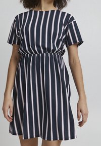 Striped dress in navy with pink and white vertical stripes. Short sleeves, round neckline, and elastic waist for a flared silhouette.