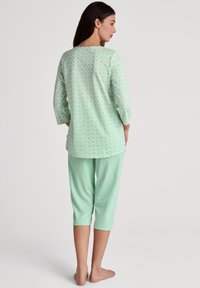 Completo pigiama verde menta composto da una maglietta a maniche lunghe con un motivo geometrico e pantaloni capri, entrambi realizzati in morbido e leggero tessuto di cotone.