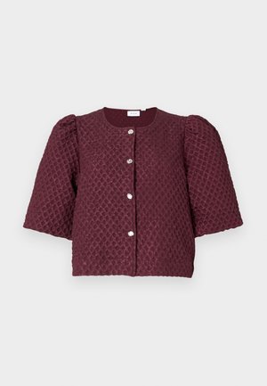 Īsa bordo struktūrēta jakas ar pūkainām piedurknēm un četriem sudraba pogām priekšpusē uz gaiša fona.