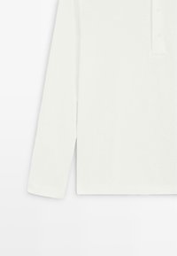 Long-sleeve white polo shirt with a textured fabric and side vent on a plain white background.