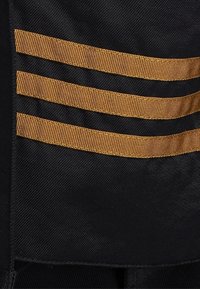 Černá látka s třemi vodorovnými pruhy zlaté stuhy. Textura se zdá hladká, s čistými okraji a jednotným designem.