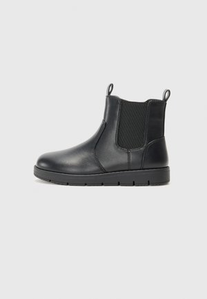 Botte cheville en cuir noir avec panneaux élastiques sur les côtés, tirettes et semelle en caoutchouc durable. Texture lisse et design minimaliste.