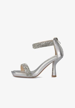 Sandalia plateada de tacón alto con puntera cuadrada, correa en el tobillo, correa frontal adornada con cristales y cierre trasero con cremallera.