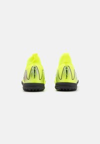 Baskets de sport jaune vif avec un ajustement confortable, dotées de semelles texturées noires et de lignes de design dynamiques. Deux boucles de tirage pour un enfilage facile.