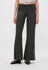 Czarne szerokie spodnie w paski z wysokim pasem. Pionowe białe paski tworzą efekt faktury. Gładka tkanina, rozszerzający się fason na dole.
